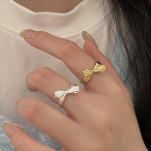 Macro detail of textured bow rings in silver and gold finish on a model hand