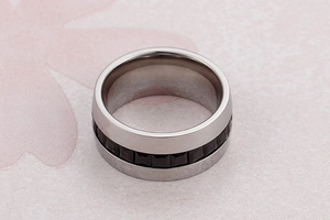 Close-up of a silver band ring with black square zircon stones and modern industrial style