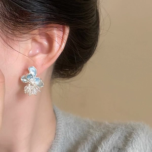 Close-up detail of an elegant blue dripping oil flower earring with pearls on a model