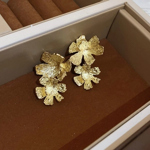 Detail view of gold layered petal earrings with hammered metal texture in jewelry box