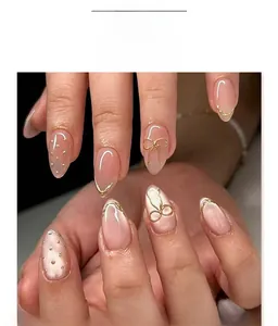 Détail macro d'ongles amande avec nœuds dorés en 3D et finition rose nude oeil de chat