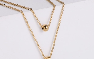 Gros plan détaillé du pendentif boule doré et de la chaîne de collier en acier titane