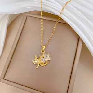 Elegant double maple leaf necklace in gold finish with diamonds on a silk background
