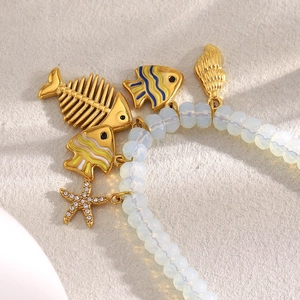 Gros plan détaillé du bracelet en perles d'opale avec breloques dorées de mer