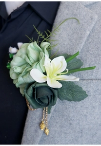 Détail d'un corsage rose verte et lys blanc avec chaîne dorée sur un costume gris
