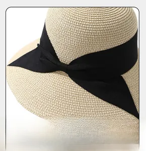 Detail of the woven straw sun hat featuring a wide brim and elegant black bow ribbon