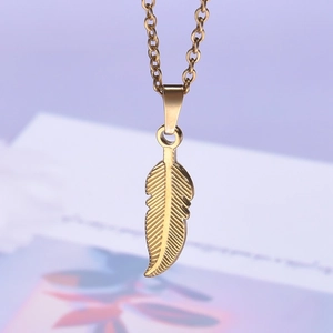 Macro shot of detailed golden feather pendant on a delicate stainless steel chain necklace