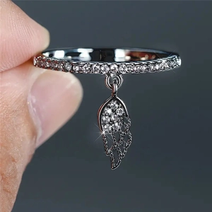 Close-up of silver ring with pavé zircons and dangling feather wing charm detail