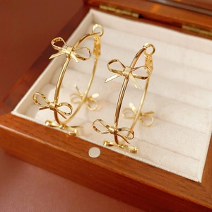 Polished gold hoop earrings with bow motifs in a velvet lined wooden jewelry box