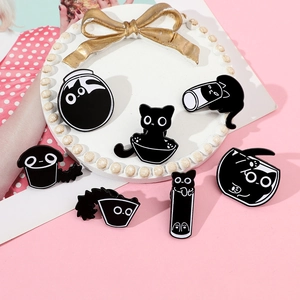 Set of seven cartoon black cat enamel pins displayed on a decorative pearl white stand