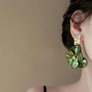 Elegant gold metal square earrings with green acrylic flower pendant on model