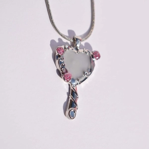 Detailed view of silver heart mirror pendant featuring small pink rose floral accents