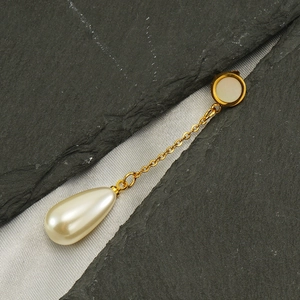 Détail de boucles d'oreilles dorées avec nacre et perle en forme de goutte d'eau