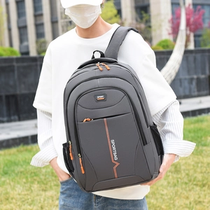Outdoor shot of a man wearing a dark grey waterproof casual backpack with orange accents