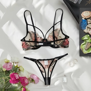 Close-up of lace lingerie set featuring butterfly embroidery and black straps on silk