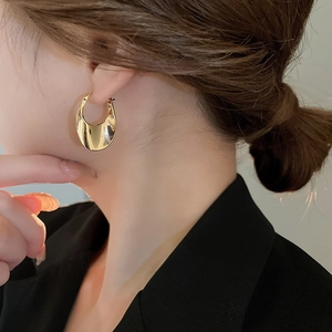 Close-up of minimalist gold oval geometric hoop earrings worn by a female model