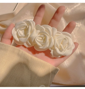 Macro detail of three elegant cream-white silk camellia flowers on a boutique hair clip