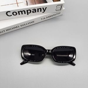 Flat lay of black oval sunglasses on books with a minimalist light grey background