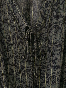 Détail d'une robe imprimée florale sombre avec rayures dorées et liens au décolleté