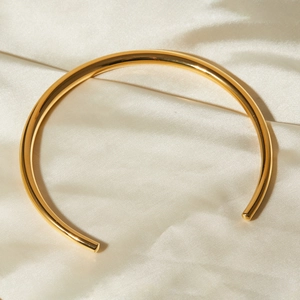 Close-up of golden minimalist oval bead choker necklace on premium beige silk fabric