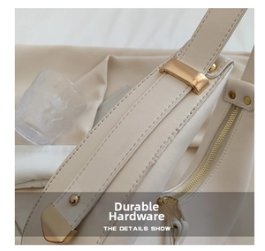Macro detail of fine stitching and gold metal buckle on a beige crescent armpit bag