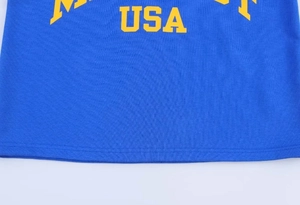 Détail d'un t-shirt bleu en coton tricoté avec l'inscription USA jaune sur le tissu