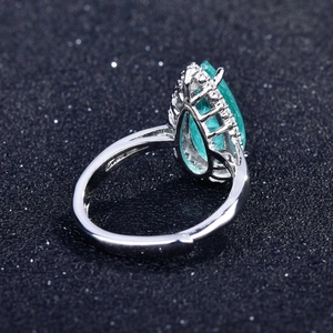 Macro shot of pear-cut emerald gemstone ring with halo diamonds and adjustable silver band