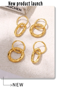 Detailed shot of gold geometric wave earrings on a textured stone surface with books