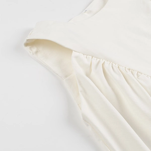 Detail of cream white sleeveless top showing neck label and gathered fabric texture