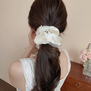 Close-up of cream satin scrunchie with pearls and beaded butterfly on a ponytail