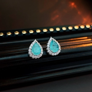 Vue macro de boucles d'oreilles goutte avec pierres bleues taille poire et halo de zircon