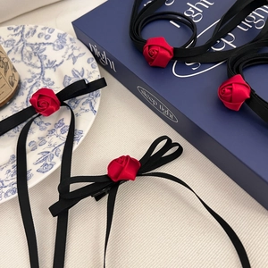 Detailed shot of handmade red silk rose hair clips with elegant black ribbon bows