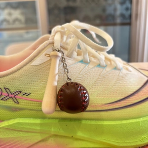 Macro view of a mini wooden baseball bat and leather ball keychain with red stitching
