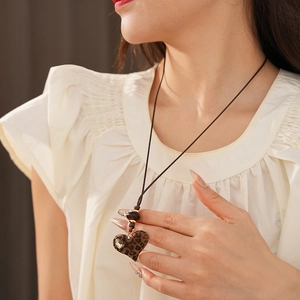 Détail du pendentif cœur en résine avec motif léopard et cristal sur cordon noir