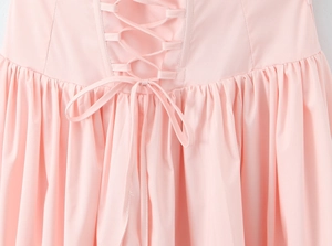 Detailed view of the lace-up corset back and bow tie on a pink summer dress