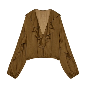 Detailed view of the ruffle trim, V-neckline, and tie-up front of this brown long sleeve top