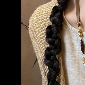 Detailed close-up of a vintage feather pendant necklace paired with beige knitwear sweater