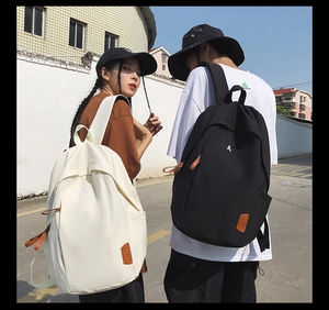 Detail of minimalist black and white backpacks featuring A-letter embroidery and leather label