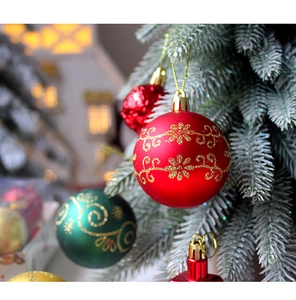 Close-up of red and green Christmas ornaments with gold glitter patterns on tree