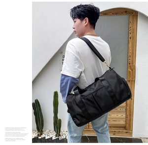 Large black sports travel bag with wet-dry separation shown on a male model outdoors