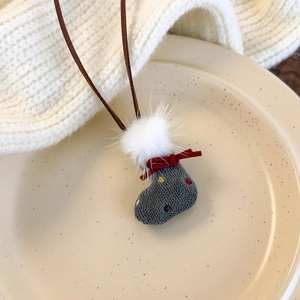 Close-up of a grey knitted Christmas sock pendant with red bow on a beige ceramic plate