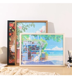 Three framed puzzles with wood frames in white, natural, and black colors on a table