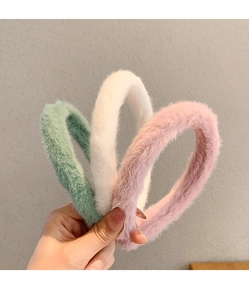 Close-up of soft plush headbands in mint green, white, and pink with fluffy texture