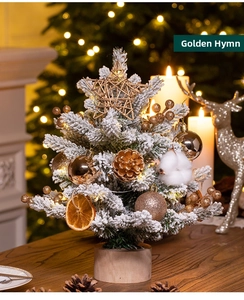 Macro detail of 30cm snow-flocked mini Christmas tree with golden balls and dried orange