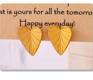 Macro view of gold-plated leaf-shaped stud earrings with intricate vein textures