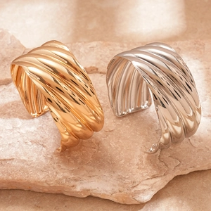 Metallic wave texture cuff bracelets in gold and silver finish on stone display