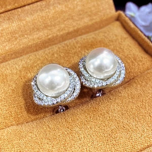 Macro detail of tear-drop pearl earrings with micro-set zircon flowers and silver swirls