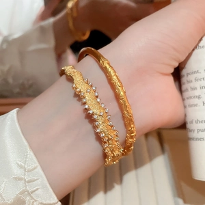 Detail of gold zircon layered bracelets featuring textured finish and embossed patterns