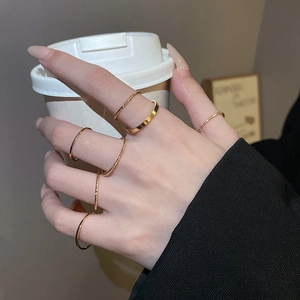 Close-up of minimalist gold ring set featuring smooth and twisted bands on hand