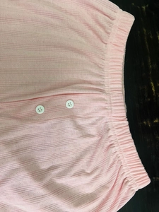 Detail of pink ribbed knit pajama shorts with elastic waist and white button decor